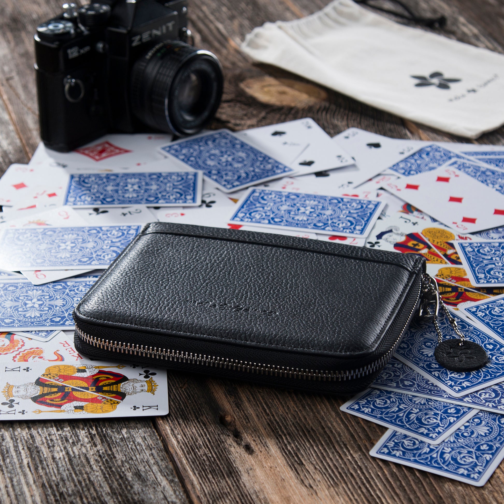 Black MELIA leather playing card case with red interior and playing cards for travel and game nights