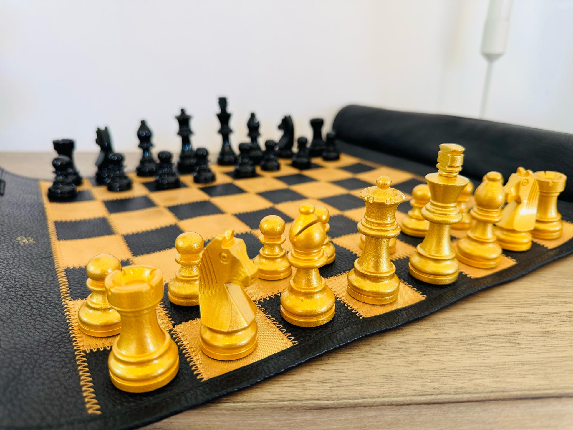 Close-up of gold magnetic chess pieces on black leather chessboard